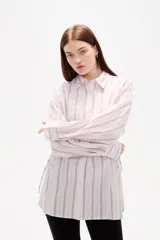 Camisa de viscosa con estampado de rayas verticales, cuello camisero, cierre frontal con botones y detalle de ajuste lateral con cordones.