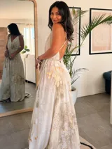 Vestido largo sin mangas con escote en V pronunciado, de corte amplio y fluido, con estampado abstracto en tonos rosados, marrones y blancos, y un cordón trenzado ajustable en la cintura.