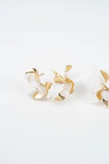 Aros tipo argolla dorados decorados con pétalos de tela roja y piezas metálicas doradas en forma de hoja.