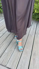 Sandalia de tacón cuadrado medio, con diseño de tiras horizontales y punta cuadrada. Presenta un acabado metalizado en color turquesa y cierre con pulsera al tobillo.