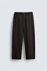 Pantalón regular fit color marrón oscuro, confeccionado en tejido con viscosa. Cuenta con cintura elástica, bolsillos delanteros y detalle de bolsillos traseros de vivo. El cierre frontal es con cremallera y botón.