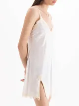 Vestido corto blanco de tirantes finos, con escote en V y detalles de encaje en el escote y el ruedo, con tajo lateral.
