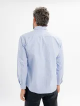 Camisa de corte regular confeccionada en tejido oxford, color azul claro. Presenta cuello con botones, cierre frontal abotonado, mangas largas con puños y un bolsillo frontal en el pecho.