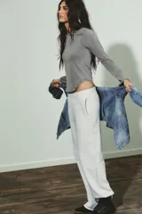 Camiseta de manga larga color gris con efecto lavado, cuello redondo y bajo redondeado. Presenta aplicaciones de tachas metálicas alrededor del escote y en el bajo.