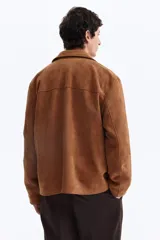 Campera marrón de tejido suave con acabado cepillado, solapas de muesca, cierre frontal de botones, bolsillos laterales insertados y canesú delantero y trasero.