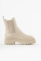 Bota tipo chelsea con suela track de goma en color marrón y capellada de cuero negro. Presenta elásticos laterales y tirador trasero.