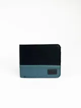Billetera Rusty modelo Lijen, de tela color negro en la parte superior y azul en la inferior, con logo de la marca en etiqueta de goma.