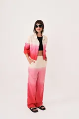Pantalón sastrero de lino con diseño degradado en tonos beige y rosado, de tiro medio-alto, corte flared y pinzas en la cintura. Cuenta con bolsillos laterales y cierre con trabilla metálica.