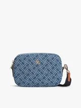 Cartera cruzada estilo cámara de Tommy Hilfiger, confeccionada en denim de algodón con estampado de monograma TH y detalles en cuero vacuno. Cuenta con cierre principal y herrajes metálicos dorados, incluyendo el monograma TH en el frente. Posee correa ajustable y extraíble.