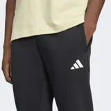 Pantalón deportivo Adidas de corte cónico, color negro con las icónicas tres tiras blancas en la parte inferior de una de las piernas y logo de la marca en el muslo. Cuenta con cintura elástica con cordón ajustable y puños acanalados.