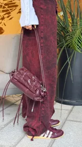Pantalón de denim con efecto lavado, de corte recto y tiro bajo. Cuenta con cordones ajustables en los tobillos para modificar la silueta y cierre frontal con botón y cremallera.