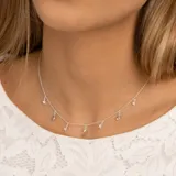 Collar plateado con cadena de eslabones y dijes colgantes: estrellas con topacios blancos, piedras redondas de topacio azul y una piedra ovalada de topacio azul en el centro.