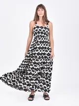 Vestido largo de corte holgado con estampado floral en tonos azul y blanco. Presenta escote cuadrado, cuerpo con frunces elásticos y falda con volados escalonados.