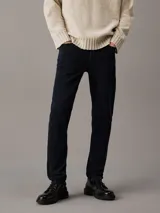 Pantalón de jean negro de corte slim taper, con bragueta con cremallera y diseño de cinco bolsillos.