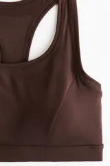Top deportivo color marrón oscuro, de escote redondo y espalda nadadora, con breteles anchos y elástico revestido en el bajo.