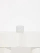 Billetera pequeña de cuero vacuno graneado con estampado de piel de serpiente en tonos grises. Tiene cierre con broche imán, divisiones internas para tarjetas y forrería de tejido jacquard. Presenta matelasseado y aplique Lipstick característico de la marca.