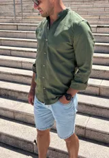 Camisa verde oliva de lino con cuello mao, manga larga y abotonadura frontal.