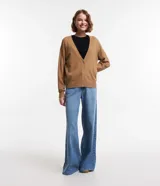 Cardigan corto de punto color marrón, con cuello en V, manga larga y cierre frontal con botones. Presenta puños y bajo acanalados.