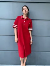 Vestido rojo de corte recto, con cuello polo, cierre de botones parcial, mangas cortas con doble franja blanca y logo bordado en el pecho.