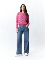 Sweater rosa de punto tramado, con cuello redondo y mangas largas.