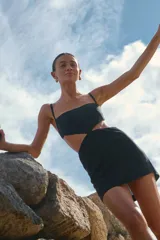 Minivestido negro de lino y rayón con escote recto, breteles regulables y espalda con tiras regulables.