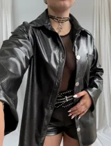 Sobrecamisa negra con textura croco, corte recto, cuello camisero, cierre frontal con botones plateados y bolsillos de parche en el pecho.