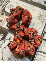 Scrunchie de tela color naranja con estampado de personajes de One Piece.