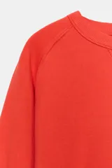 Buzo rojo de cuello redondo y manga larga, con efecto lavado y detalle de costura triangular en el cuello.