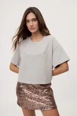 Remera gris de fit amplio, con mangas cortas y cuello redondo. Presenta efecto lavado y estampa frontal con aplicación de strass con la frase "fiesta mode on".