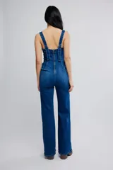 Mameluco de denim elastizado azul, entallado en el cuerpo con pierna bootcut. Presenta escote cuadrado, bolsillos plaqué delanteros, tiras anchas y cierre en la espalda.
