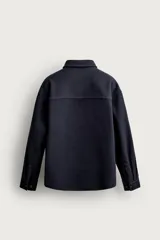 Sobrecamisa de ajuste relajado en color azul marino, con cuello de solapa, manga larga con puño abotonado y cierre frontal con botones. Presenta bordados contrastantes en el frente con la inscripción "St. Louis Worldwide Goods" en tonos naranja y blanco.