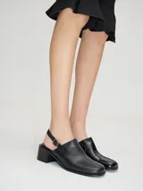 Zuecos de cuero vacuno con acabado en charol, color beige. Presentan un diseño clásico con taco cuadrado de madera de 5 cm y correa trasera ajustable con hebilla metálica.