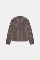 Camisa de manga larga con cuello subido, cierre frontal con botones y detalle de volantes en el pecho. Presenta un diseño a rayas verticales y puños elásticos.