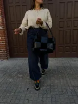 Cartera de hombro confeccionada en cuero y gamuza con diseño de damero, combinando paneles de texturas lisas y aterciopeladas. Presenta una manija trenzada y detalles de costuras artesanales en los laterales.