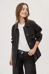 Campera de jean oversize de color negro gastado, con cuello clásico, cierre frontal con botones metálicos y bolsillos con solapa en el pecho.