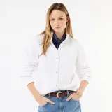 Blusa blanca de manga larga con cuello alto con volantes y cierre frontal de botones con ribetes dorados.