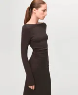 Vestido largo de color marrón, de corte recto, con escote bote y mangas largas. Presenta un diseño ajustado con sutil fruncido a los lados en la zona de la cintura.