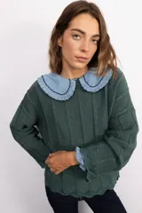 Sweater de punto color verde oscuro con destellos de lurex, diseño oversize, cuello bebé de tela celeste con volados y bordes decorativos, y puños con detalle de volado en tela celeste.