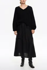 Falda midi de color negro con corte en línea A y diseño con vuelo. Presenta bolsillos plastrón delanteros y cintura ajustable con cordón. Confeccionada en tejido con textura de mezcla de viscosa y lyocell.