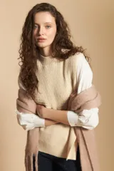 Chaleco de tejido de punto en color crema, con cuello alto y diseño acanalado. Presenta una silueta relajada con aberturas laterales.