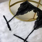 Portaligas negro confeccionado en lycra y encaje, con tiras elásticas ajustables y broches metálicos.