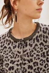 Cardigan de punto con estampado animal print en tonos gris y negro. Presenta cuello redondo con detalle de pedrería brillante, cierre frontal con botones y puños acanalados.
