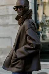 Chaqueta de cuello solapa y manga larga, con diseño de doble faz que combina tejido efecto ante y borreguillo. Cuenta con cierre frontal de botones y bolsillos delanteros.