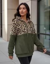 Buzo tipo canguro de polar, con diseño combinado en animal print de leopardo en la parte superior y color gris claro en la parte inferior. Cuenta con capucha, cordones ajustables y cierre frontal.