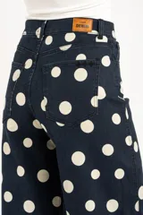 Jean de corte baggy y tiro alto, confeccionado en denim azul marino con estampado de lunares blancos, estilo barrel.