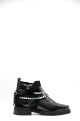 Bota corta tipo chelsea de cuero negro, con paneles laterales de gamuza y suela plana de goma. Presenta un diseño minimalista con tirador en la parte trasera.