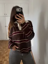Sweater de tejido bremer doble, con diseño a rayas horizontales en tonos marrón, bordó y beige, con cuello polo blanco y escote en V.