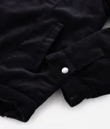 Campera de pana negra con cuello de sherpa blanco, cierre frontal por cremallera y bolsillos delanteros con solapa y botón. Presenta forro interno de sherpa para mayor calidez.