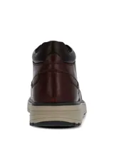 Botín de cuero color bordó con diseño clásico, cierre mediante cordones y suela de goma en tono beige. Presenta una estructura robusta con cuello acolchado y punta redonda.