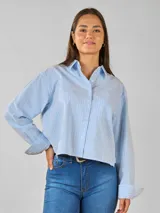 Camisa celeste a rayas verticales blancas, estilo crop, de corte holgado y manga larga.